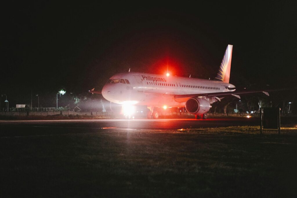 A passenger airplane with red lights parked at night on a runway, showcasing transportation theme.